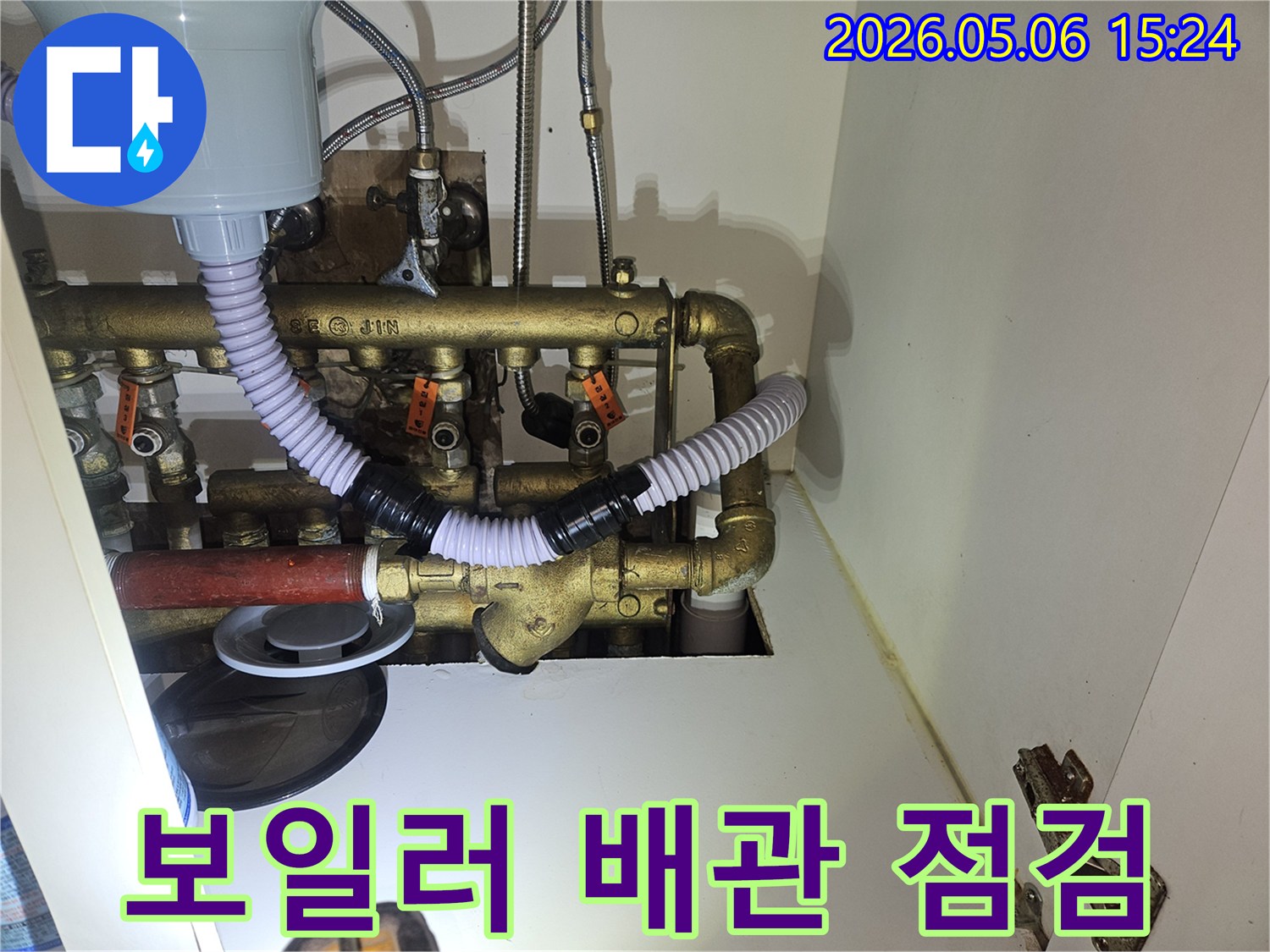 이 이미지는 주방 하부장-내부에 위치한 보일러-관련 배관 시스템에서-누수 여부를 확인하고-있는 전문적인 점검 과정을-보여주고 있습니다.