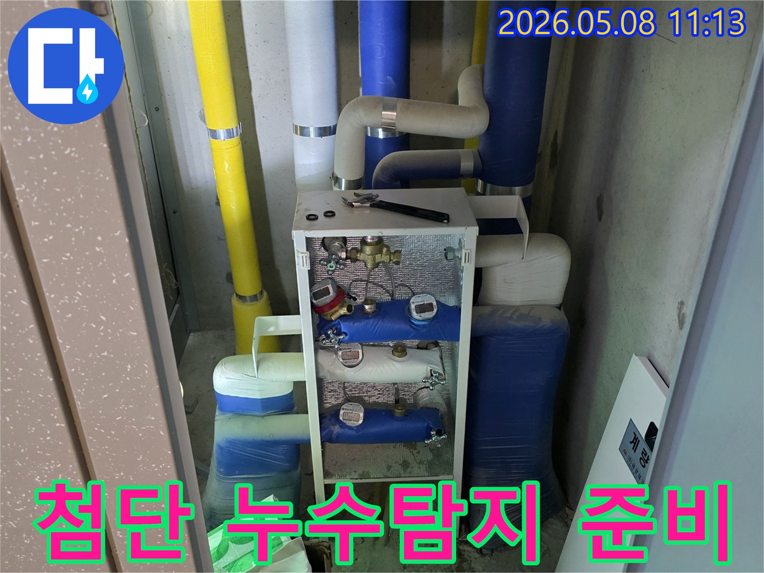 이 이미지는 건물의 유틸리티 공간에 있는-다양한 배관과 계량기-그리고 작업 도구를 보여주며-이는 전문적인 누수탐지 작업이-진행될 준비가 되었음을 나타냅니다