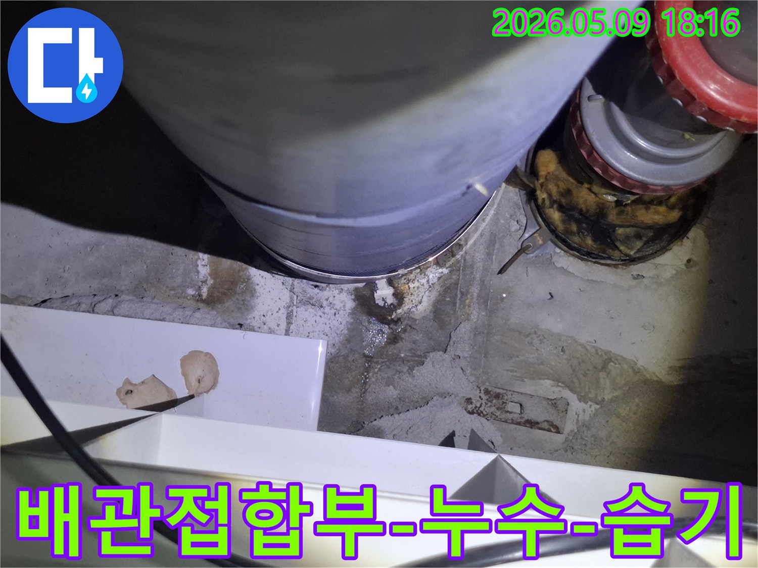 이 사진은-오래된 배관의-접합부에서-물이 새어-주변 콘크리트가-젖은-상태를-보여줍니다