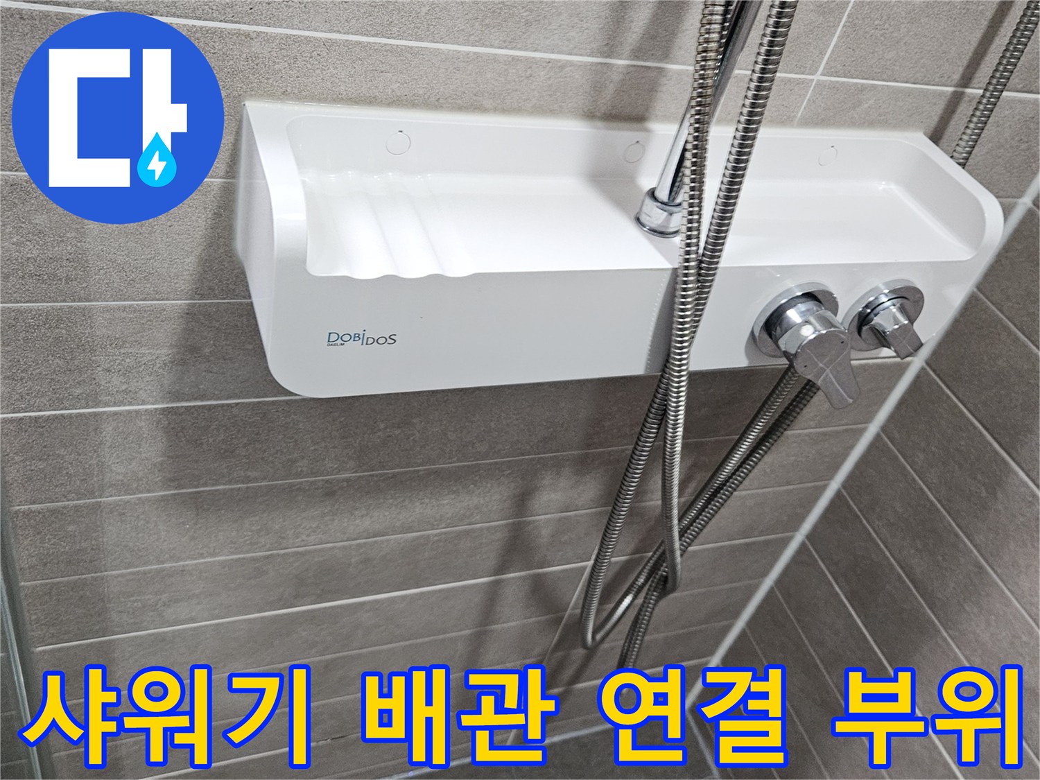 금속 샤워 호스와 수전 핸들이 설치된 욕실 벽면의 근접 사진입니다.