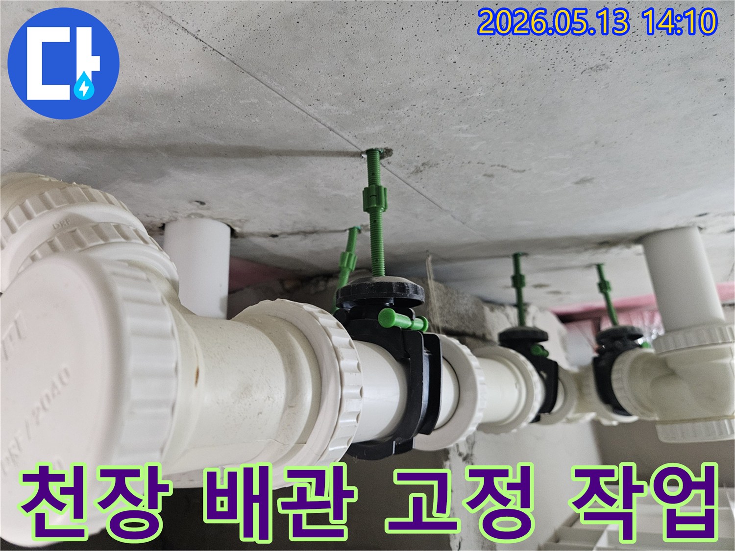 콘크리트 천장에 견고하게 고정된 하얀색 배관과-배관 중간에 설치된 검은색 밸브의 디테일한 모습