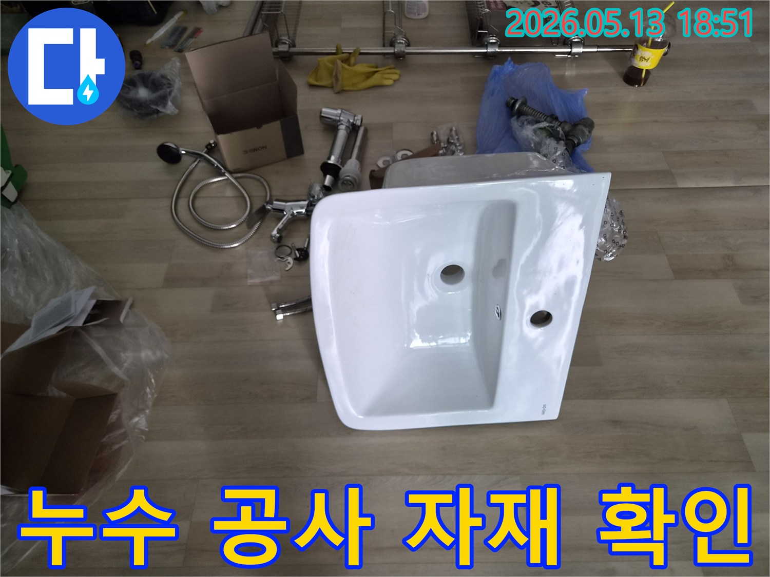 누수 공사를 위한-새 세면대와-다양한 수도 부품들이-바닥에 가지런히 놓여있습니다.