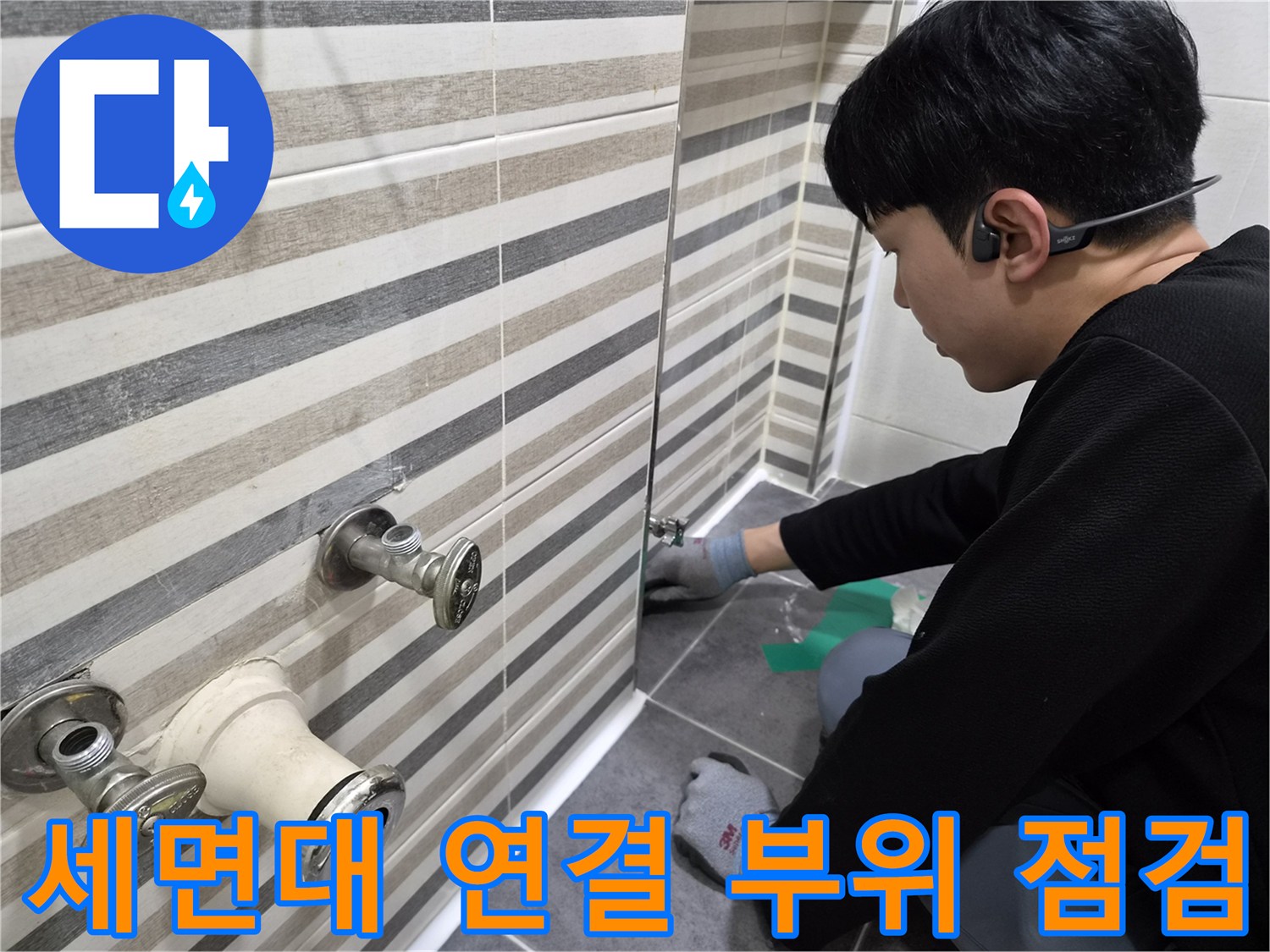 벽면 타일 사이로 노출된 세면대용 배관과 수전의 상태를 보여주는 사진입니다.