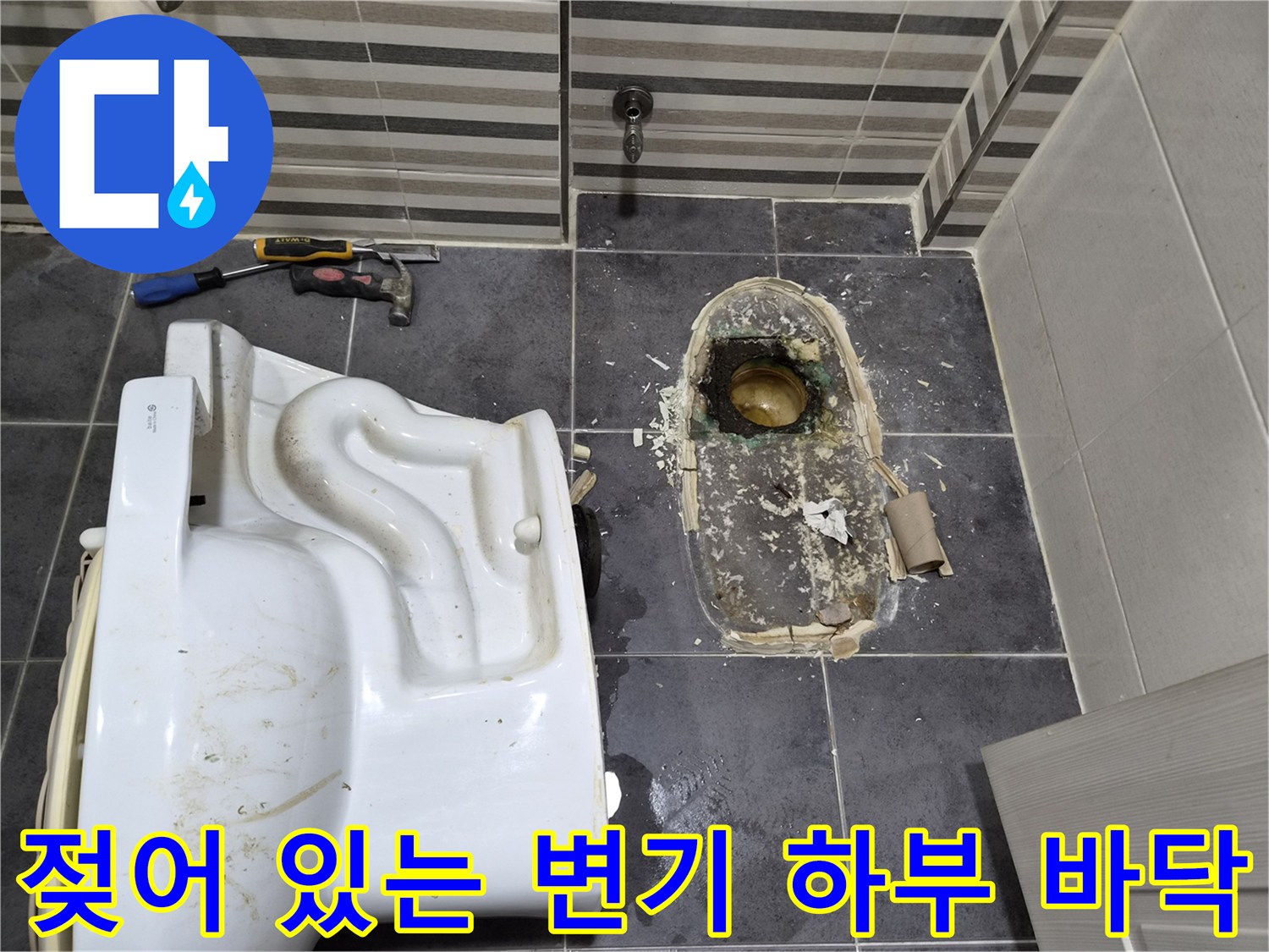 변기를 제거한 후 드러난 젖은 타일과 배관 부위 사진입니다.