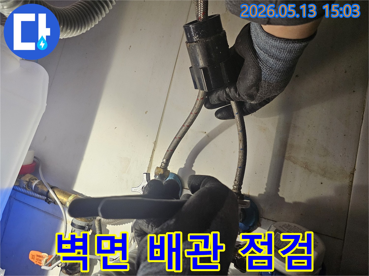 전문 기술자가-벽면 안쪽의-수도 배관 연결 부위를-꼼꼼하게 점검하며-누수 흔적을-찾아내고 있습니다