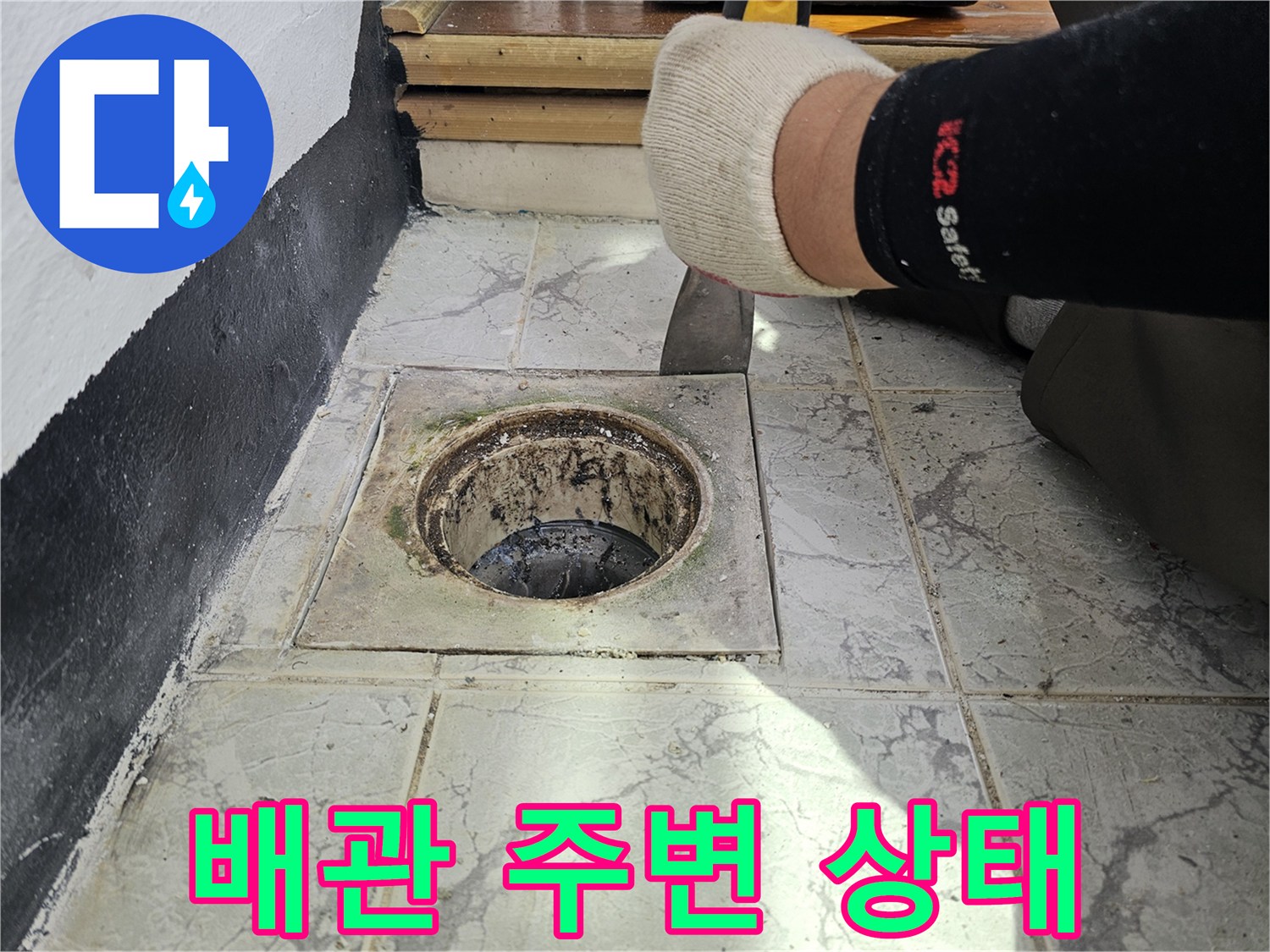 우수관 배관과 바닥 타일 사이의 오염된 틈새를 촬영한 사진입니다.
