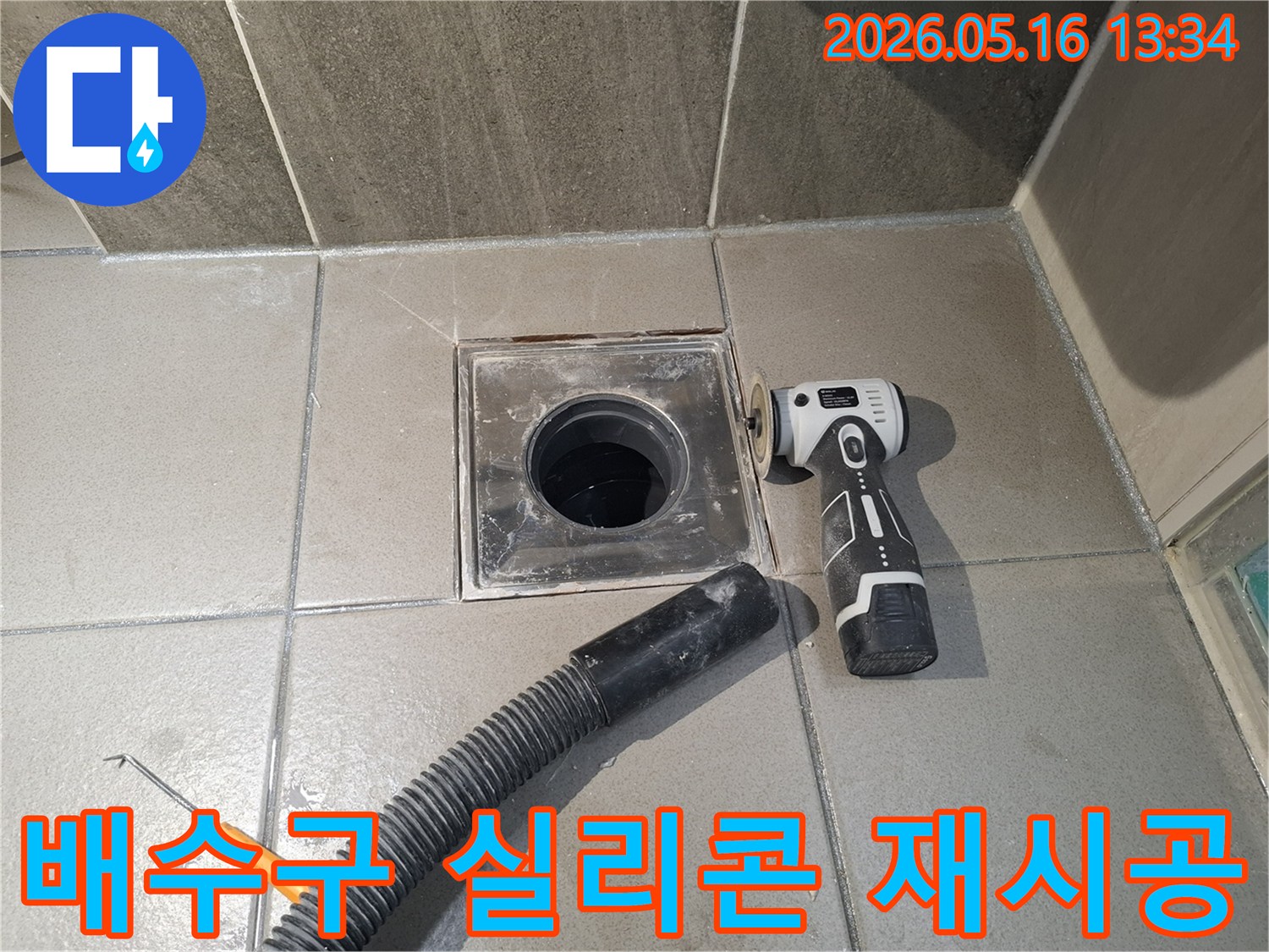 전문 엔지니어가 욕실 배수구 주변의 실리콘 누수를 해결하기 위해-낡은 실리콘을 전동 공구로 제거하고-흡입 호스로 현장을 깨끗하게 정리하는 중입니다