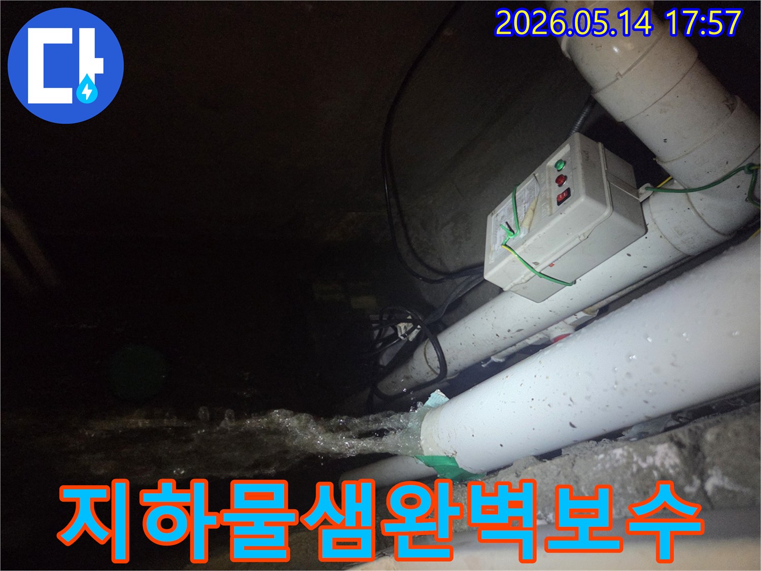 어두운 지하 공간에서-파이프에서 물이 강하게 뿜어져 나오는-지하 배관 물샘 현장을 보여주는 사진입니다-전기 제어 박스와 배관들이 함께 보입니다.