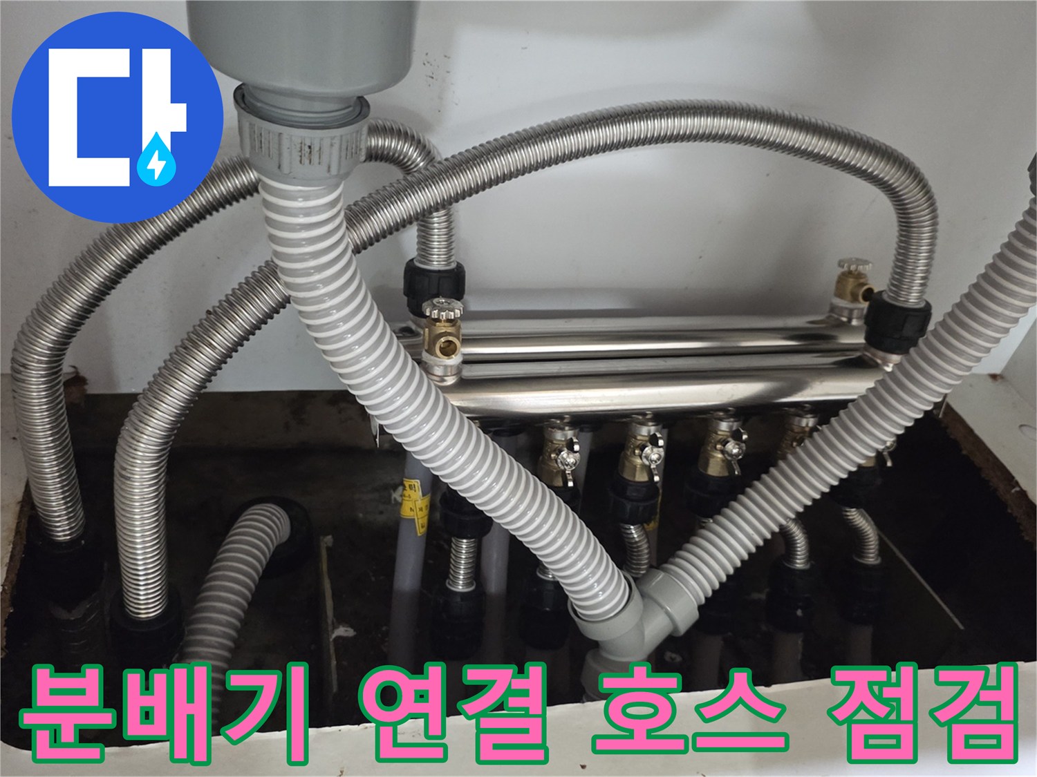 싱크대 하부의 분배기와 은색 주름관들이 모여 있는 작업 현장 모습입니다.