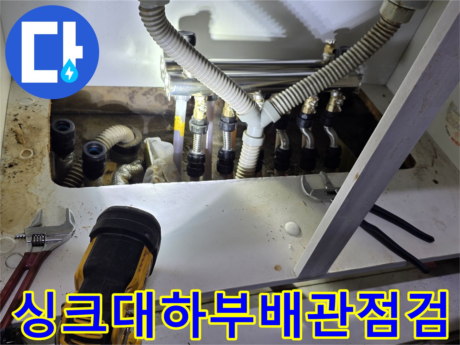 싱크대 하부장 내부 분배기 밸브와 배관 연결 부위를 촬영한 사진입니다.