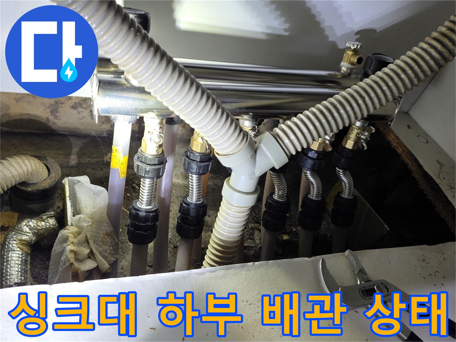 주방 싱크대 하부장 내부의 보일러 분배기와 연결된 주름관 및 배관 점검 모습