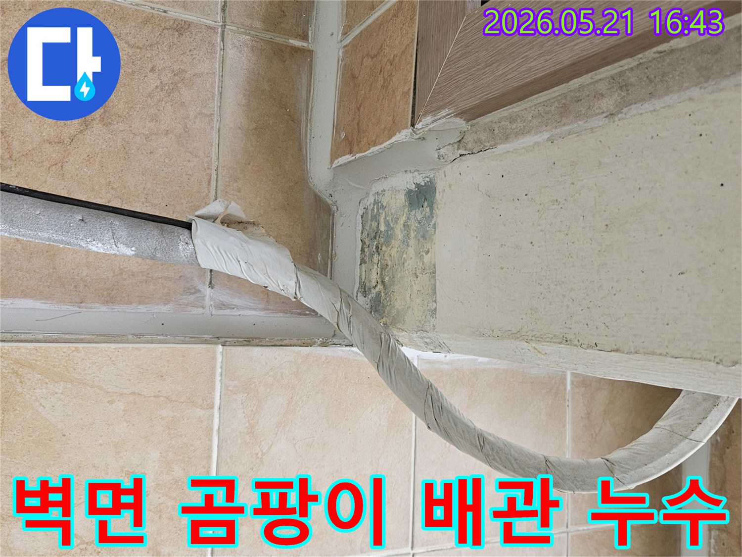 이 이미지는-포천 신북면 아파트의-벽면 하단에-위치한-단열 처리된-배관 주변의-습기와-녹색 곰팡이-흔적을-보여주며-배관 누수-가능성을-시사합니다