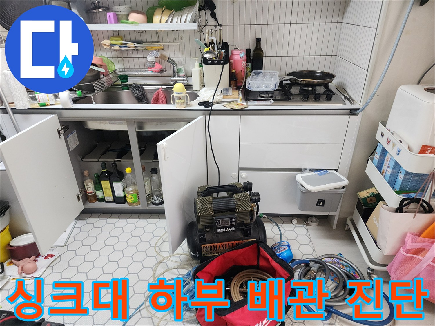 주방 싱크대 아래 공간에 배치된 누수 탐지용 장비와 공구들