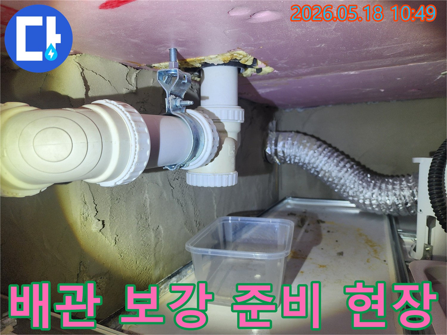 이 사진은 누수 배관 아래에 임시 물받이를 설치하고-배관 손상 예방 및 보강 작업을 준비하는 현장입니다