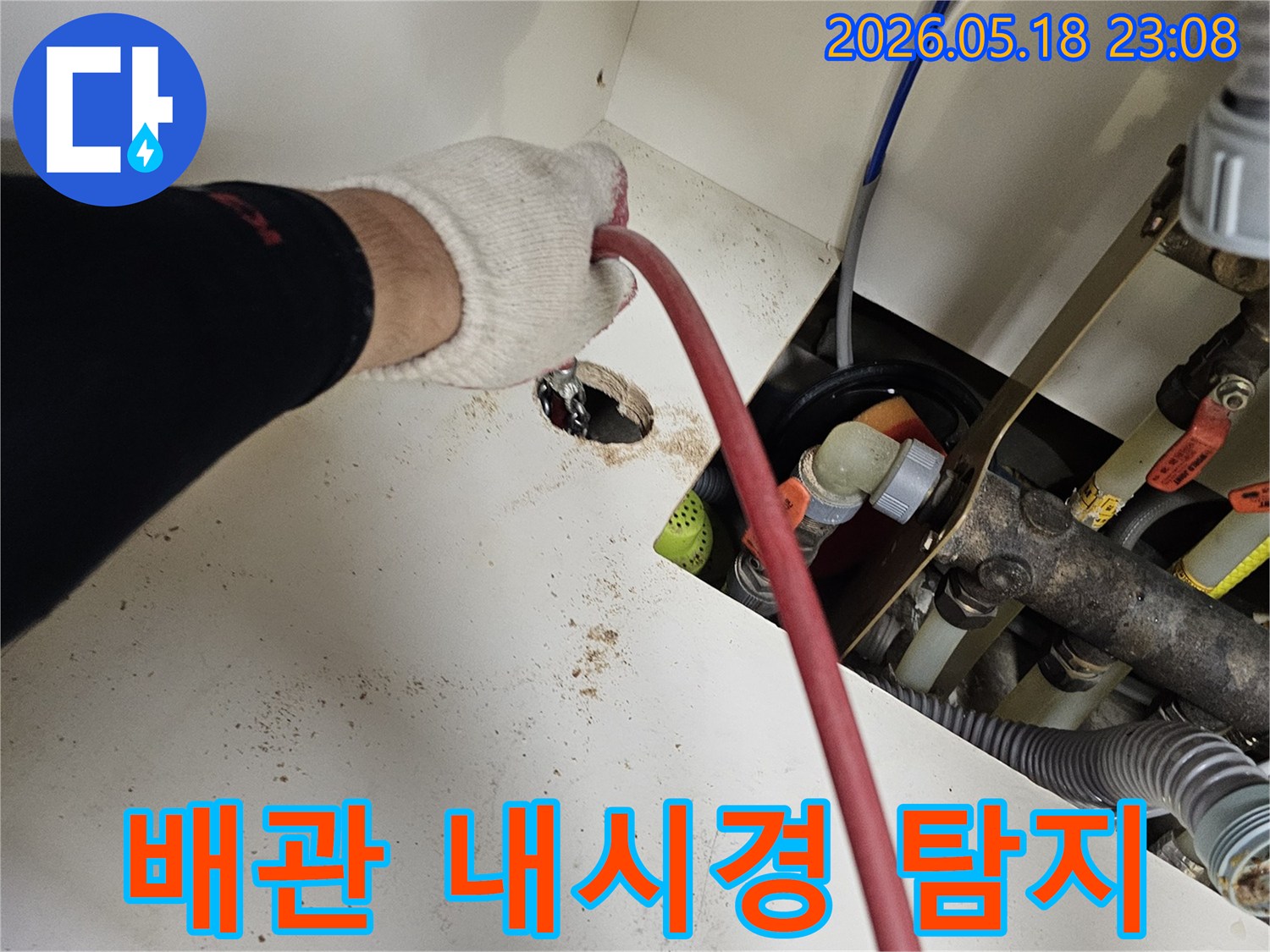 전문가가-작업용-장갑을-끼고-배관-내부-탐지용-내시경-케이블을-삽입하는-모습