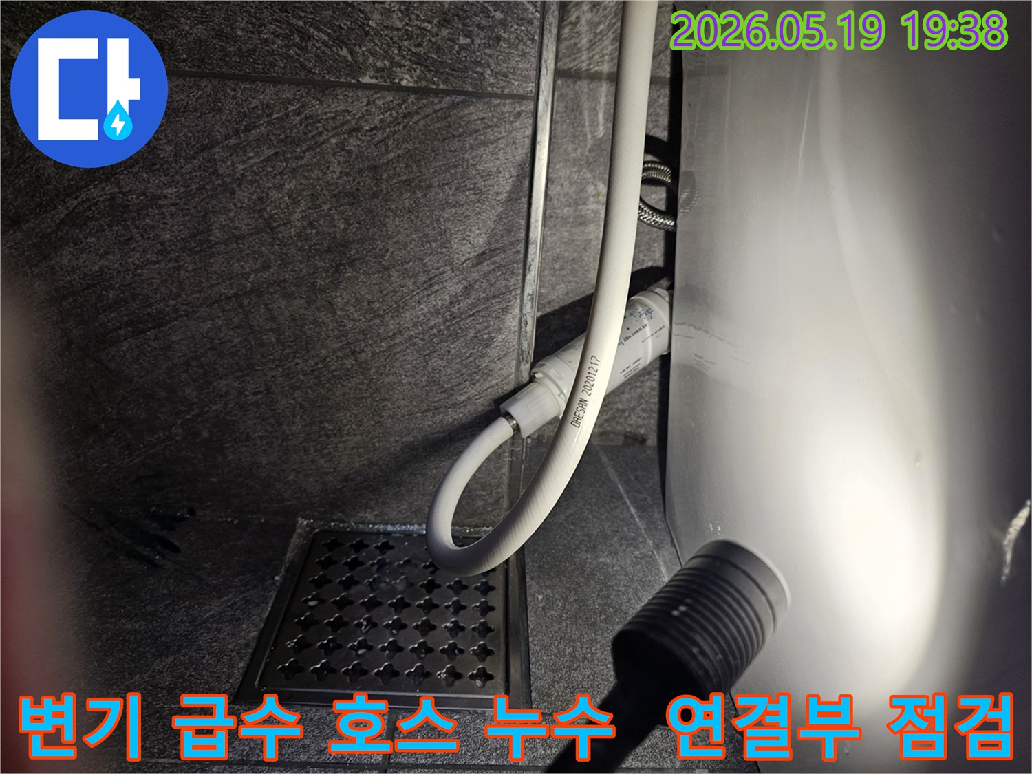 이 사진은-수지구 아파트 화장실에서-변기 급수 호스의 누수 여부를-플래시로 비추며-세밀하게 점검하는 현장을 보여줍니다.