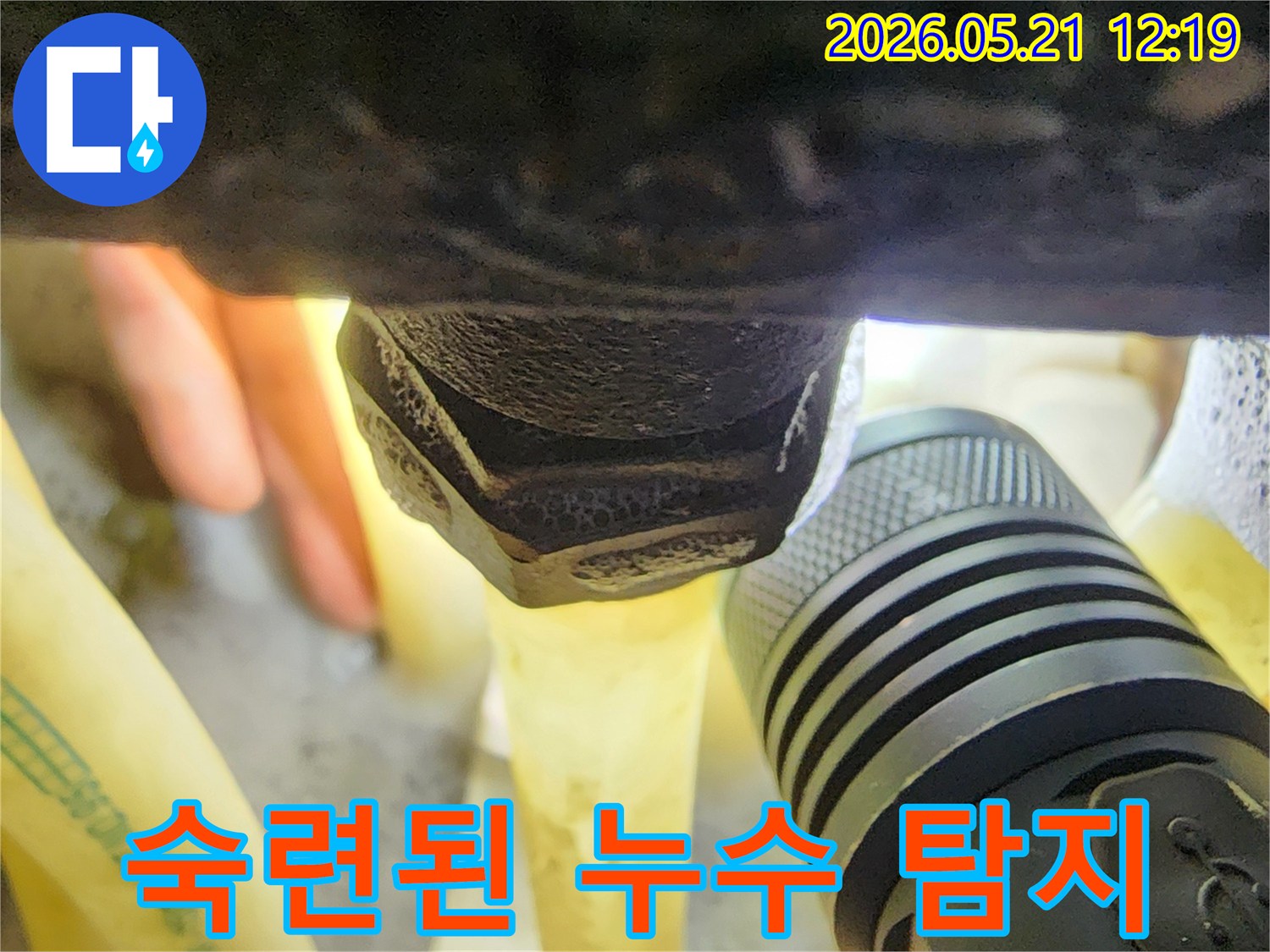 어두운 공간에서-플래시를 이용해-배관 연결부의-미세한 누수 흔적을-숙련된 기술로-찾아내는 과정입니다.