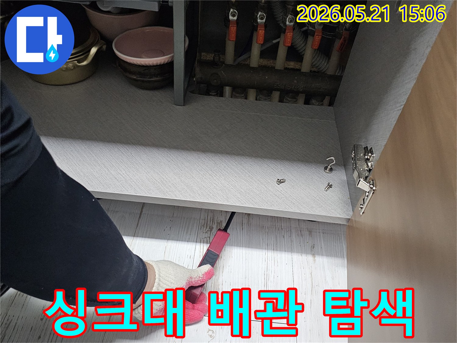 누수 탐지 전문가가-싱크대 하부의-배관 연결부를-세심하게 탐색하고 있습니다