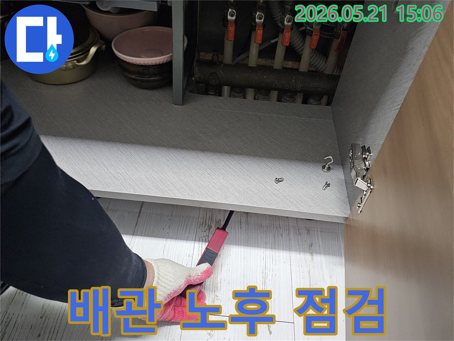 숙련된 엔지니어가-싱크대 하부의-노후된 배관 연결부를-세심하게 점검하고 있습니다
