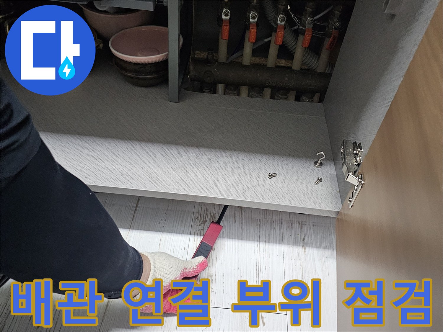 싱크대 밑 배관 뭉치와 작업 도구를 사용하는 모습