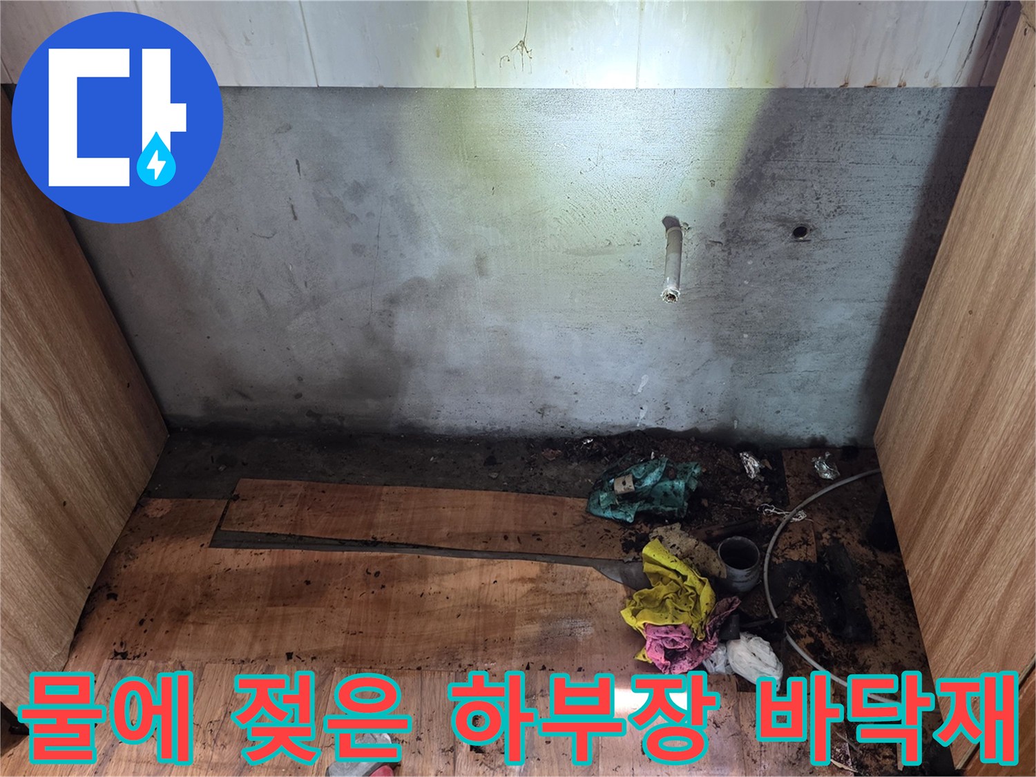 싱크대 하단 배관 부위-누수로 인해 검게 변한 나무판과 습기