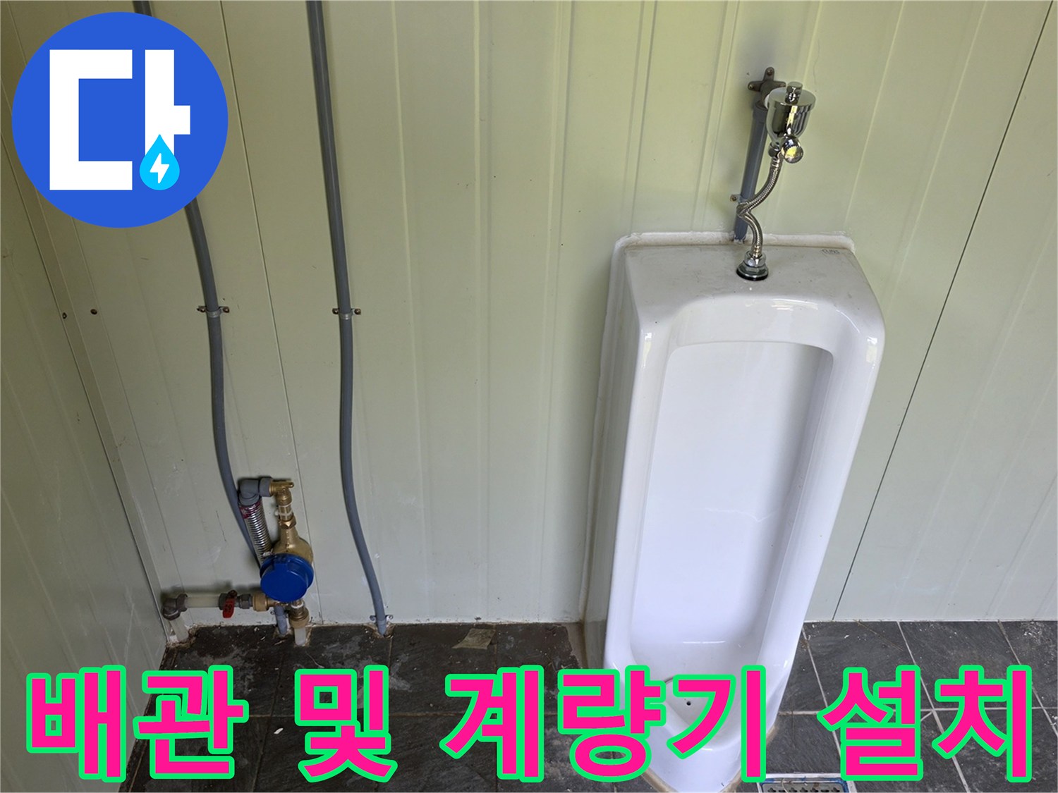 벽면 배관과 소변기 하단에 설치된 수도 계량기의 근접 사진입니다.