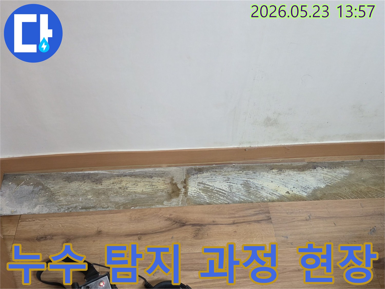 누수 탐지 장비와 함께-벽 하단에 발생한-습기와-변색된-벽면의-상태를-보여주는-누수 현장 이미지