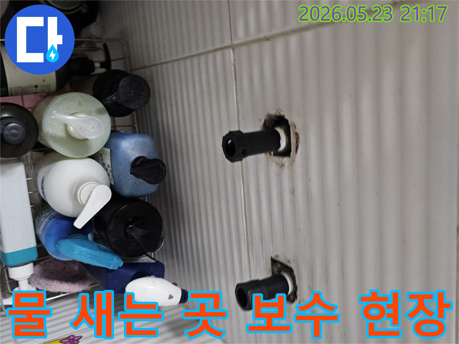 타일 벽면에서 노출된 수도 배관의 연결 부위에서-물이 새는 곳을 정밀 탐지 후 보수하기 위해-점검하는 모습입니다.