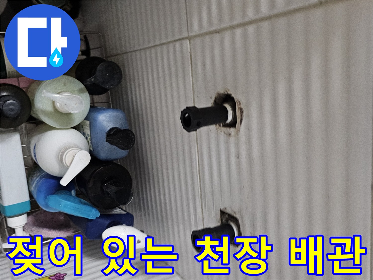 흰색 천장 패널에 설치된 검은색 배관과 주변의 젖은 흔적