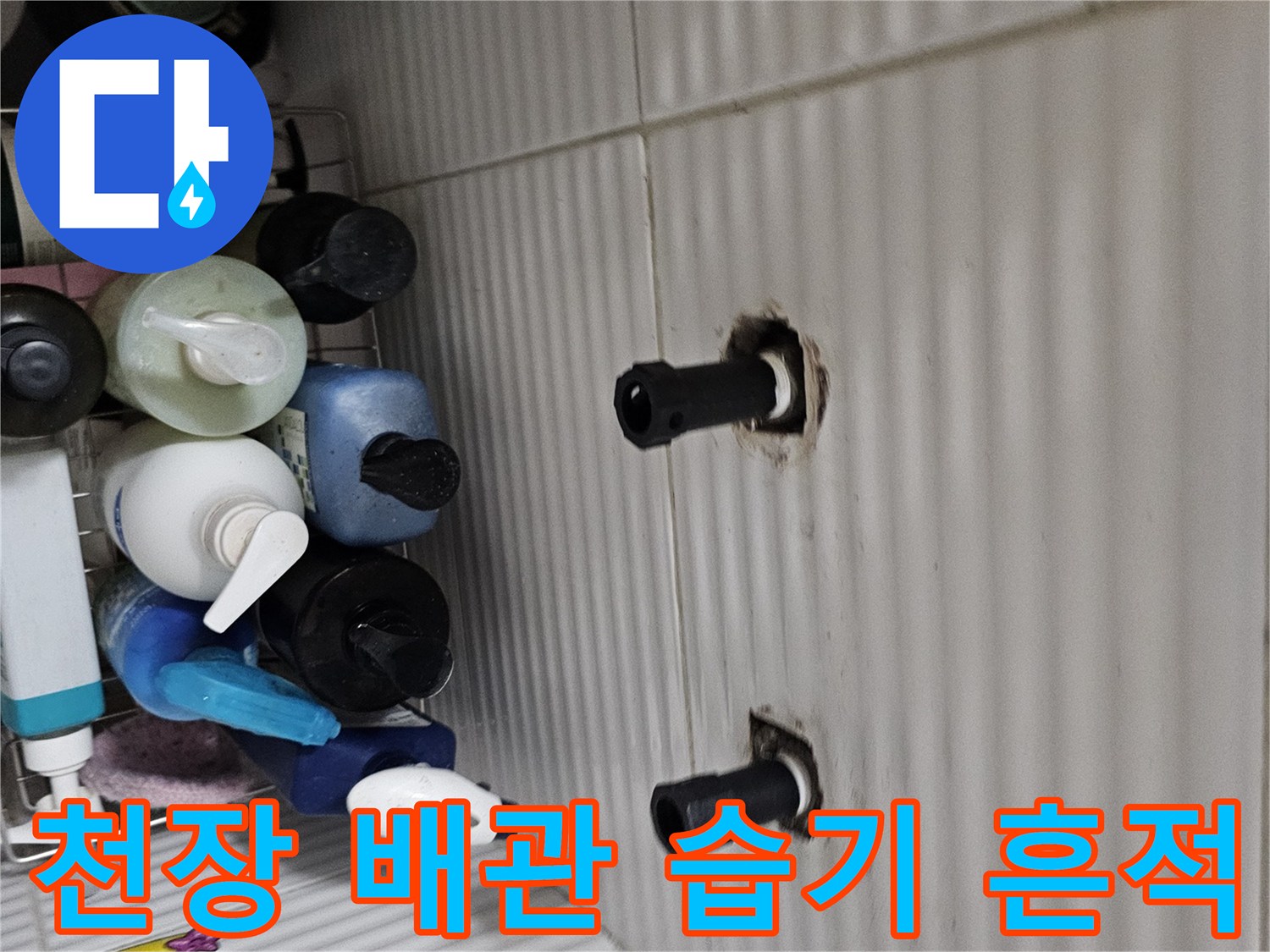흰색 타일 천장에 노출된 검은색 배관과 젖은 마감 부위