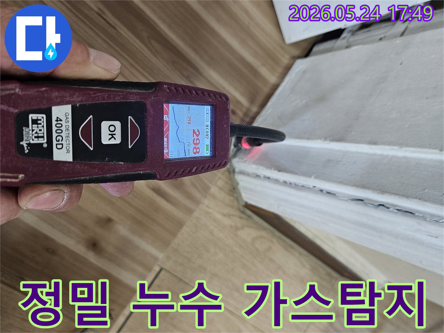 누수 엔지니어가 가스 탐지 장비를 이용해 벽면과 바닥 경계의 누수 흔적을 면밀히 조사하고 있습니다.