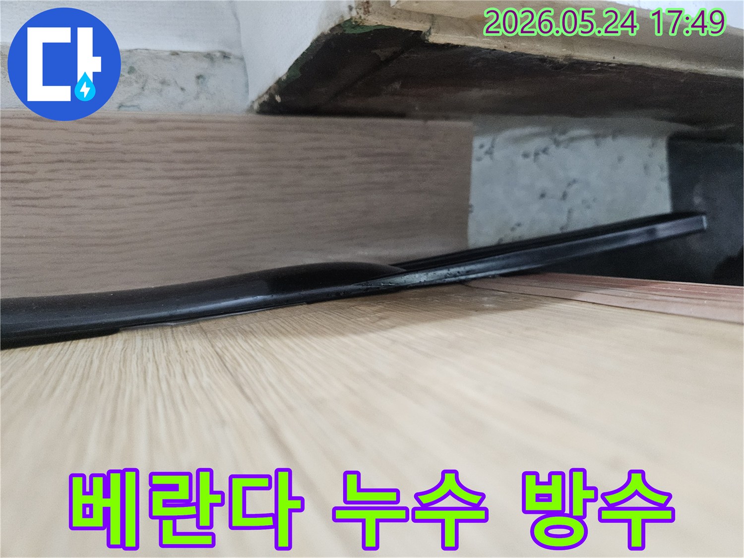 마루 틈새와-그 아래-습기 찬-모습은-베란다에서-외부 물이-유입되어-발생한-누수일 수 있으며-방수 작업이-필요합니다