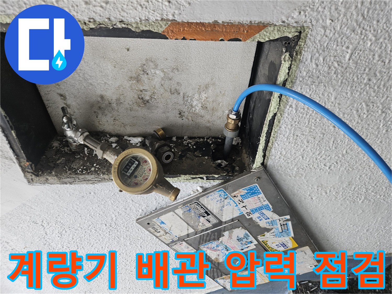 벽면 안쪽 계량기와 파란색 호스가 연결된 점검 모습입니다.