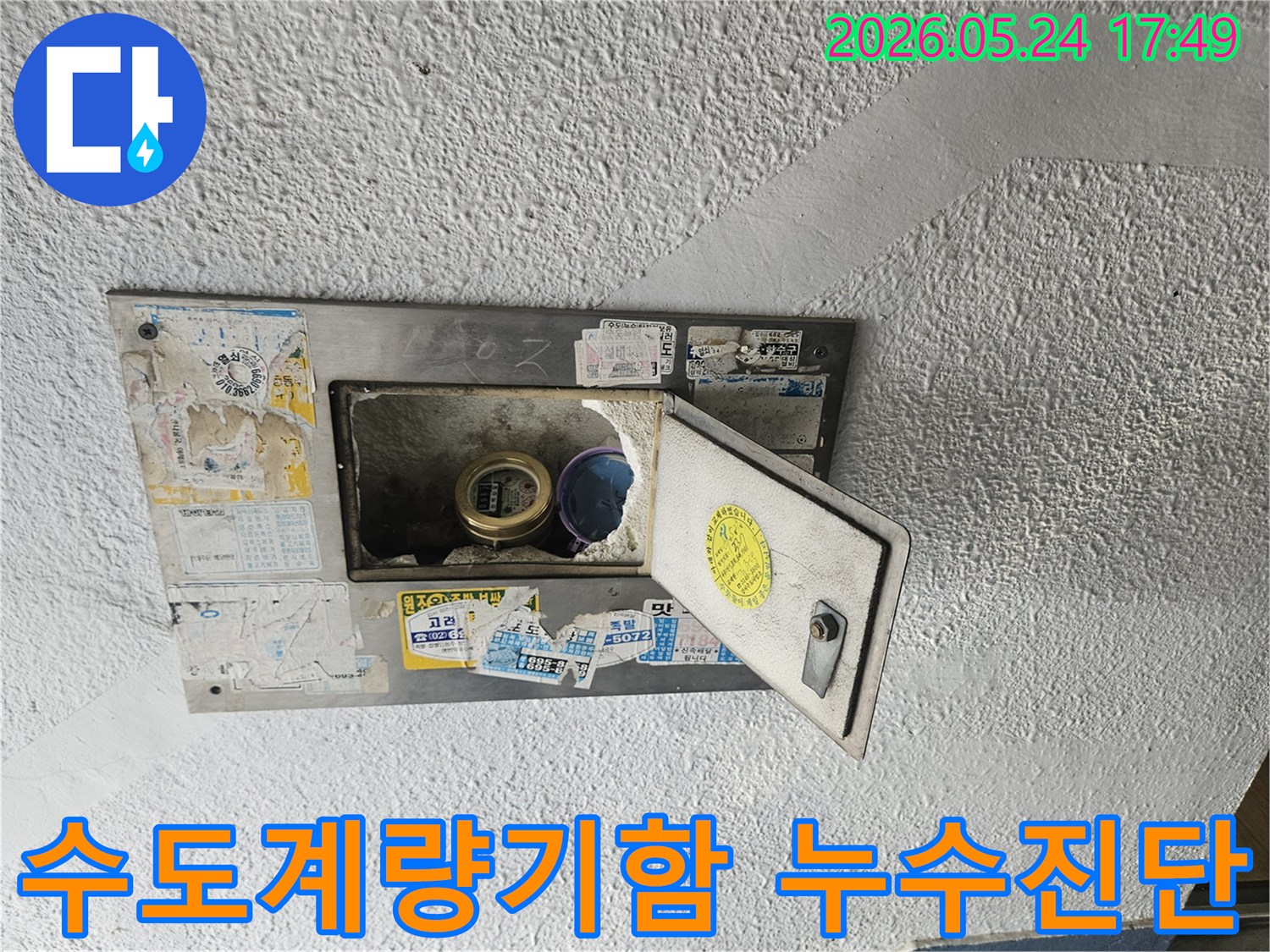 오래된 수도계량기함이 열려있고-내부의 수도계량기가 보이는-누수 현장을 보여주는 이미지입니다.