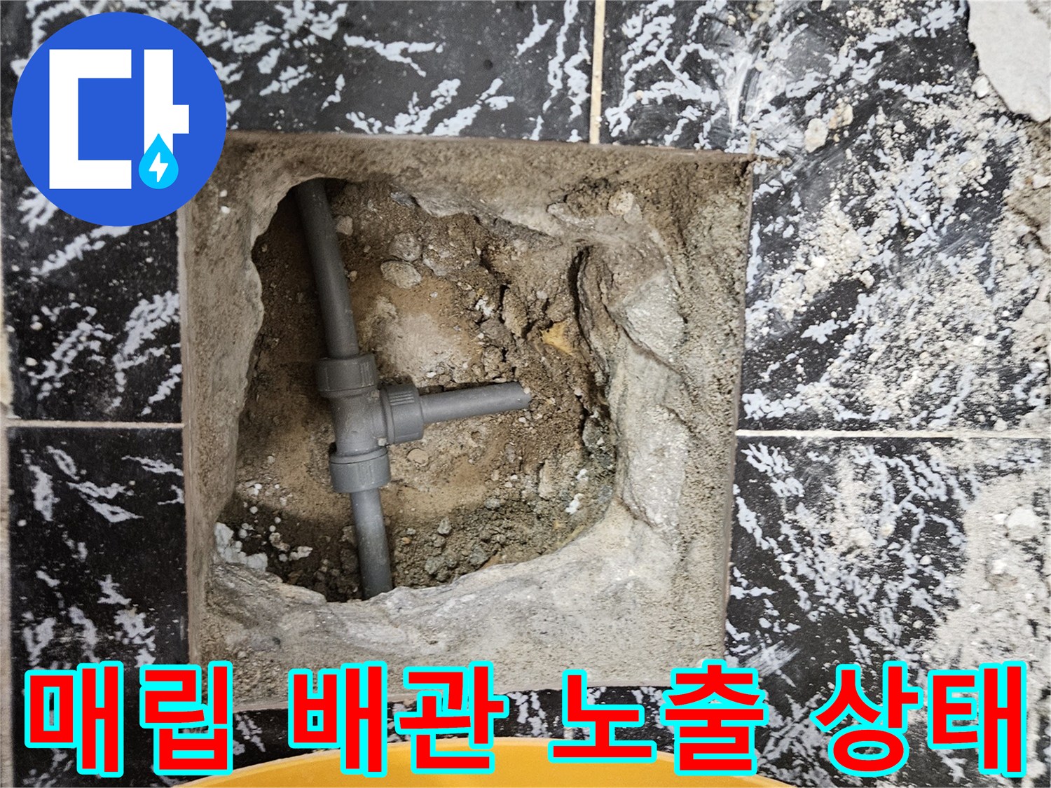 콘크리트 층 아래 드러난 검은색 수도 배관 부속