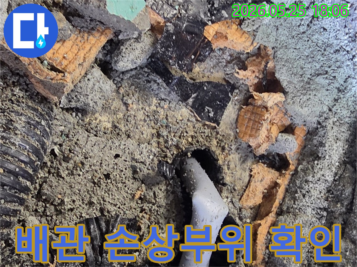 파쇄된 바닥 아래에서 드러난 젖은 배관과 주변의 흙-콘크리트 조각들이 누수 탐지 및 수리 과정을 보여줍니다.