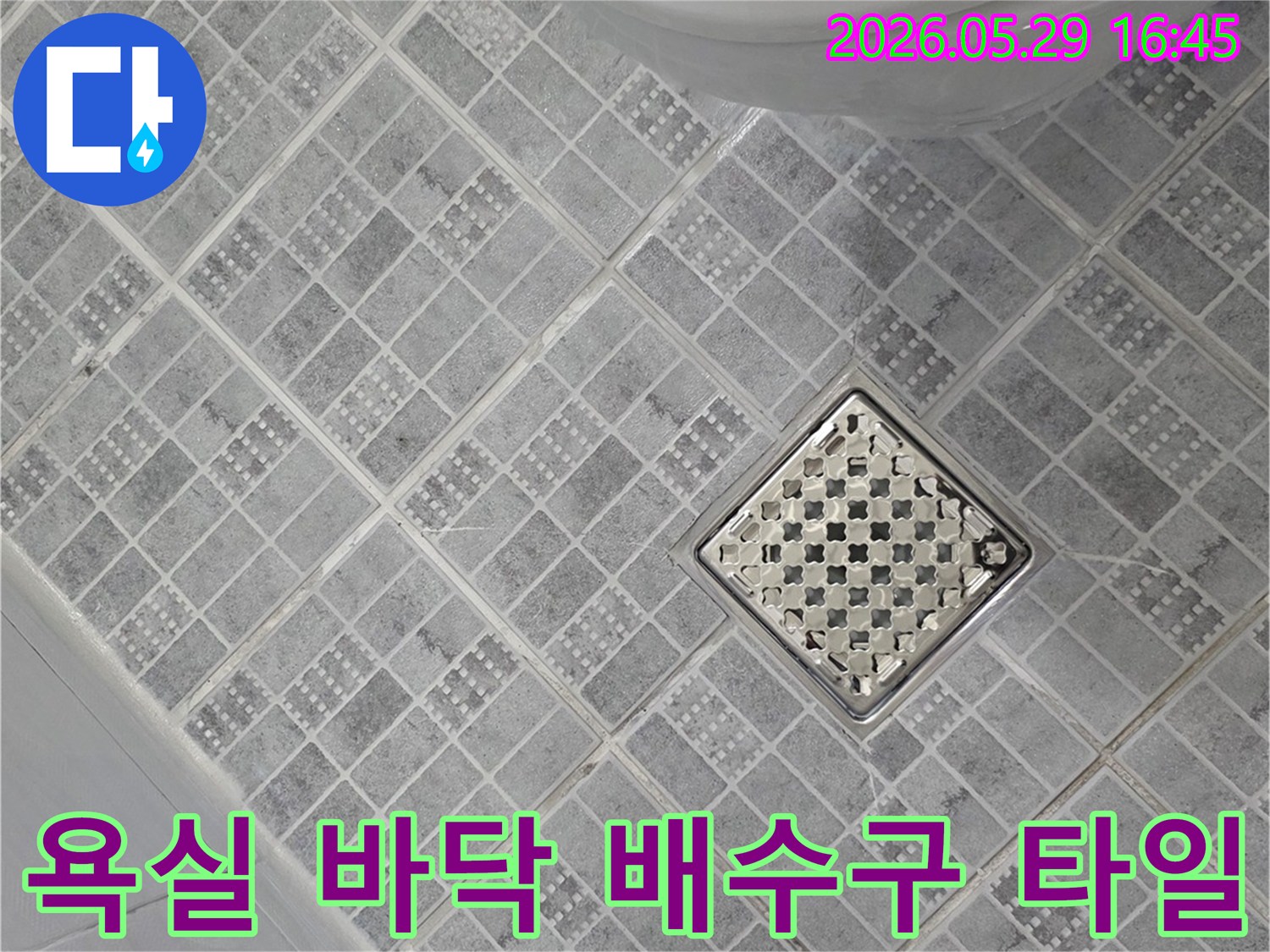 욕실 바닥의 회색 타일과-중앙의 스테인리스 배수구-그리고 변기 일부가 보이는-누수 점검 현장 사진