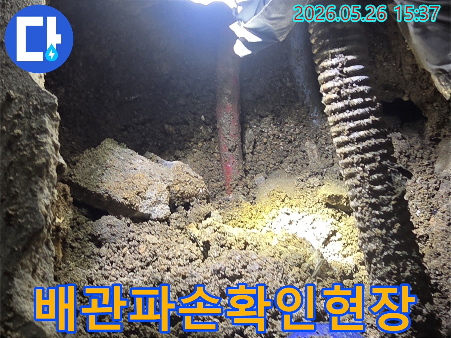누수-탐지-전문가가-어두운-굴착-현장에서-손전등으로-배관-파손-부위를-정밀하게-확인하는-과정