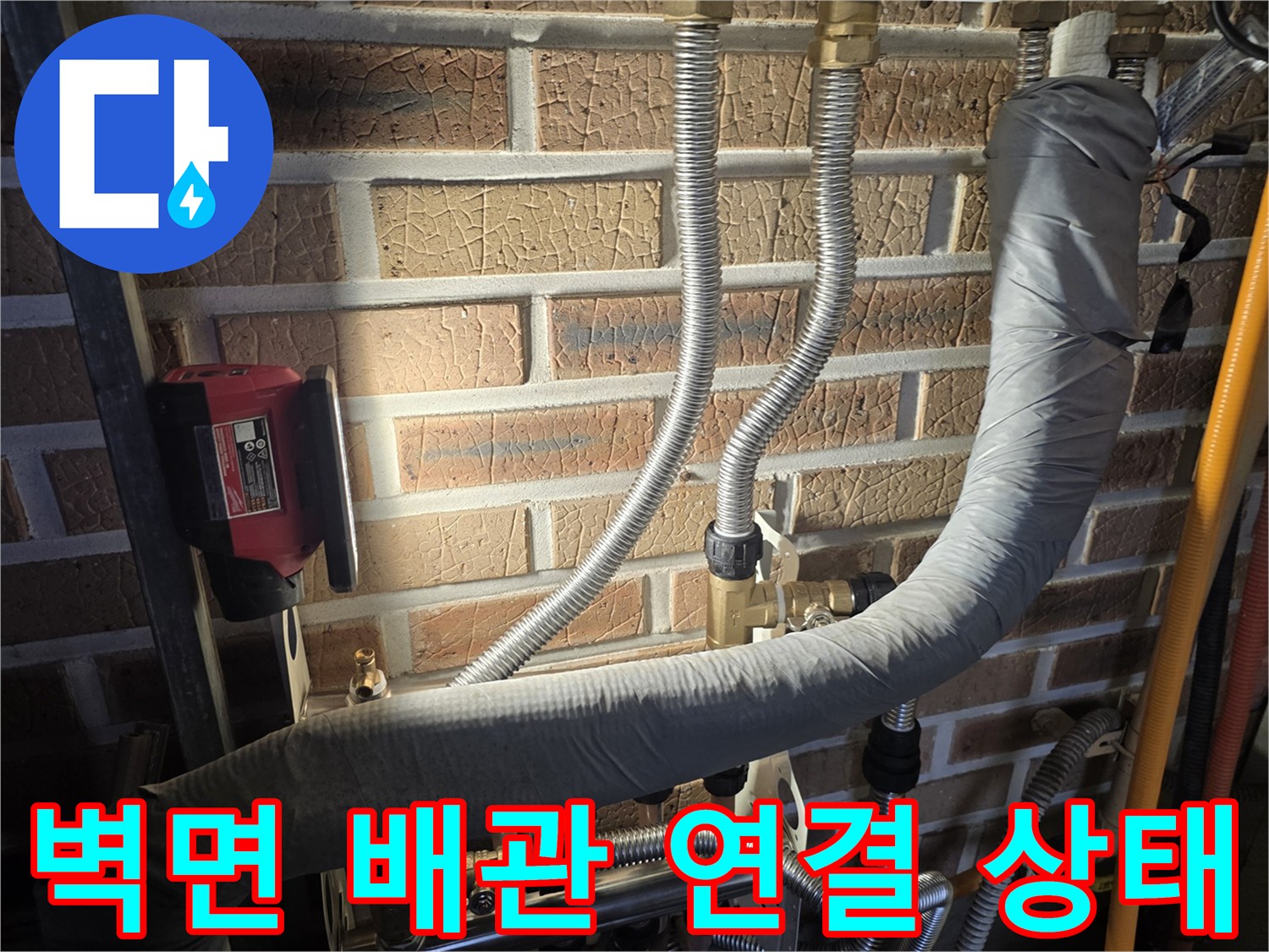 벽돌 벽면에 설치된 은색 주측 관과 보온재 마감 배관