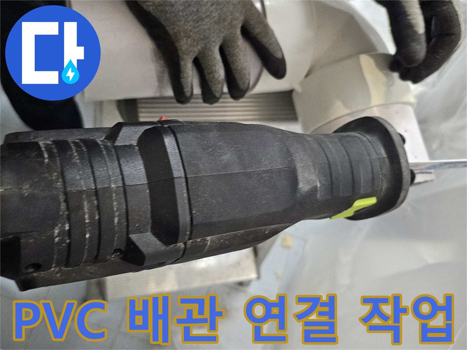 작업자가 전동 공구로 배관 연결부를 조이는 모습
