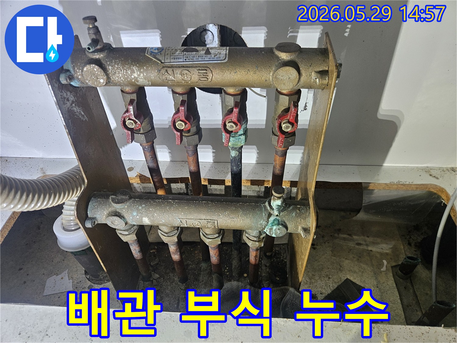 오래된 아파트의 난방 분배기에서-심각한 부식과 함께 누수 흔적이 발견되어-전문가가 교체 작업을 준비하고 있습니다.