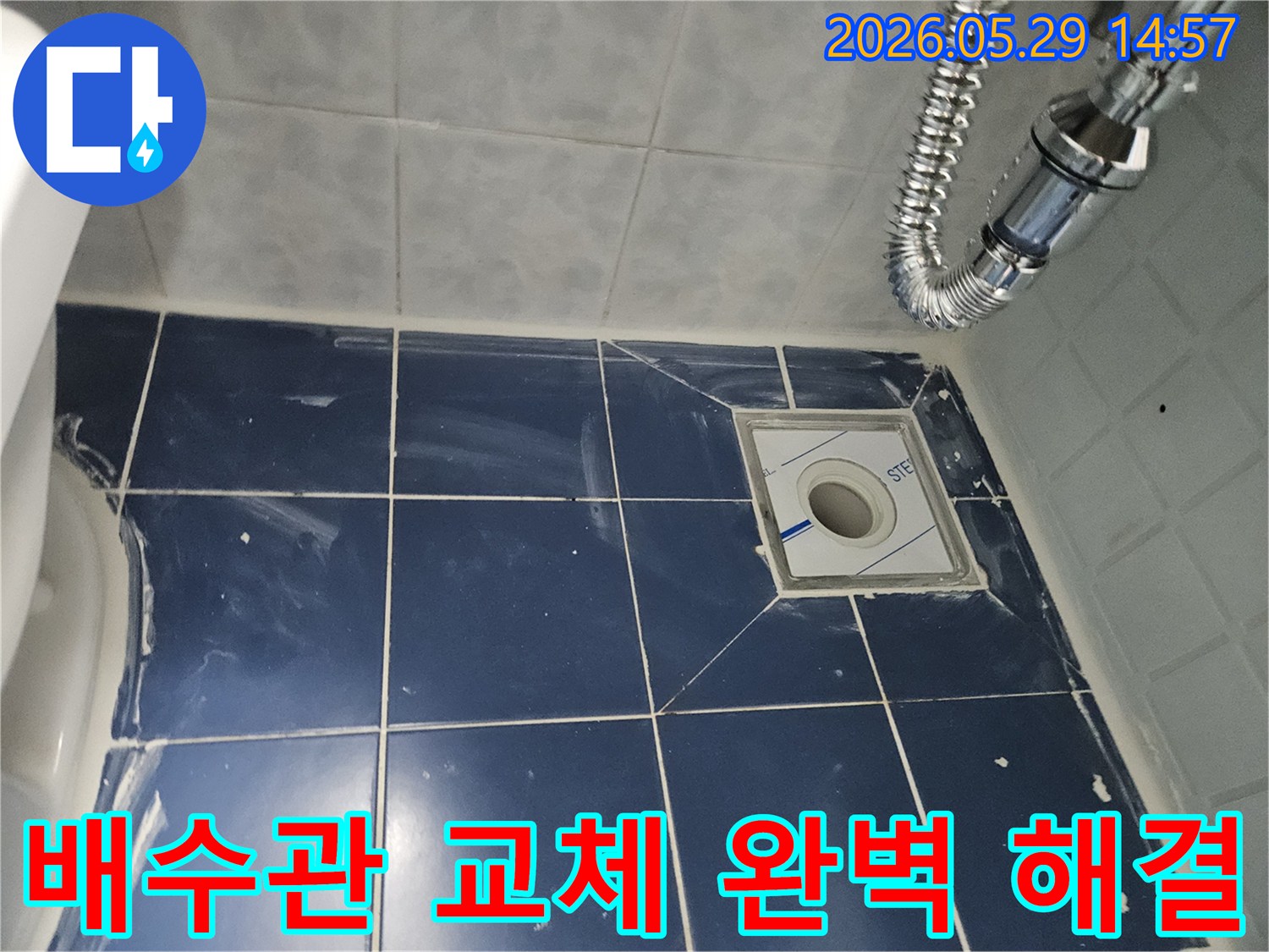 욕실 바닥의-새로운 배수구와-주변 타일-그리고 견고하게-연결된 유연한-배수관이-보이는-누수-해결-현장-사진입니다