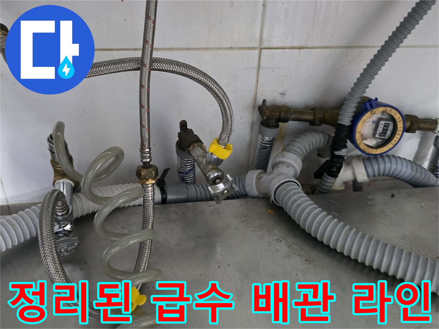 주방 하부의 정돈된 냉온수 배관과 계량기 부속품들