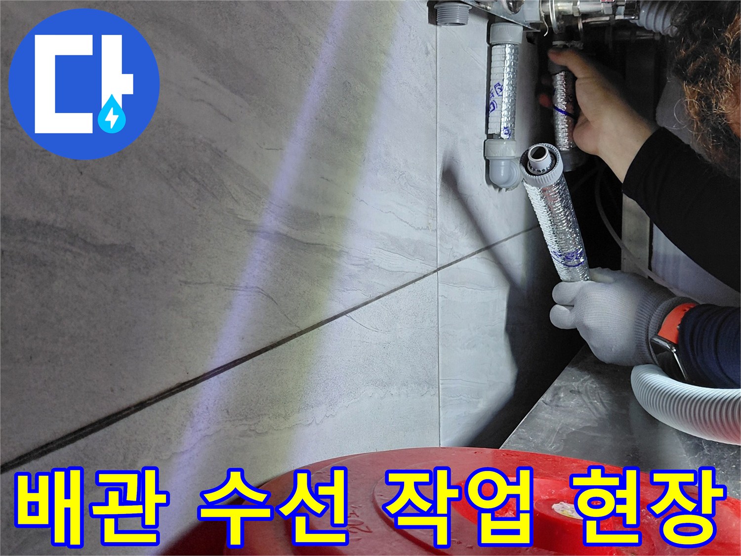 손전등으로 밝게 비춘 싱크대 하부 에이콘 배관의 연결 상태