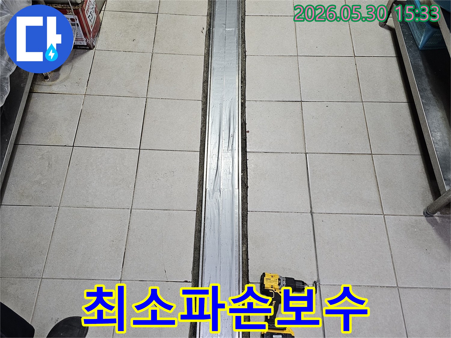 타일 바닥과-배수 트렌치-그리고 작업용 전동 드릴이 놓인-최소 파손 원칙의-누수 보수-준비 현장입니다