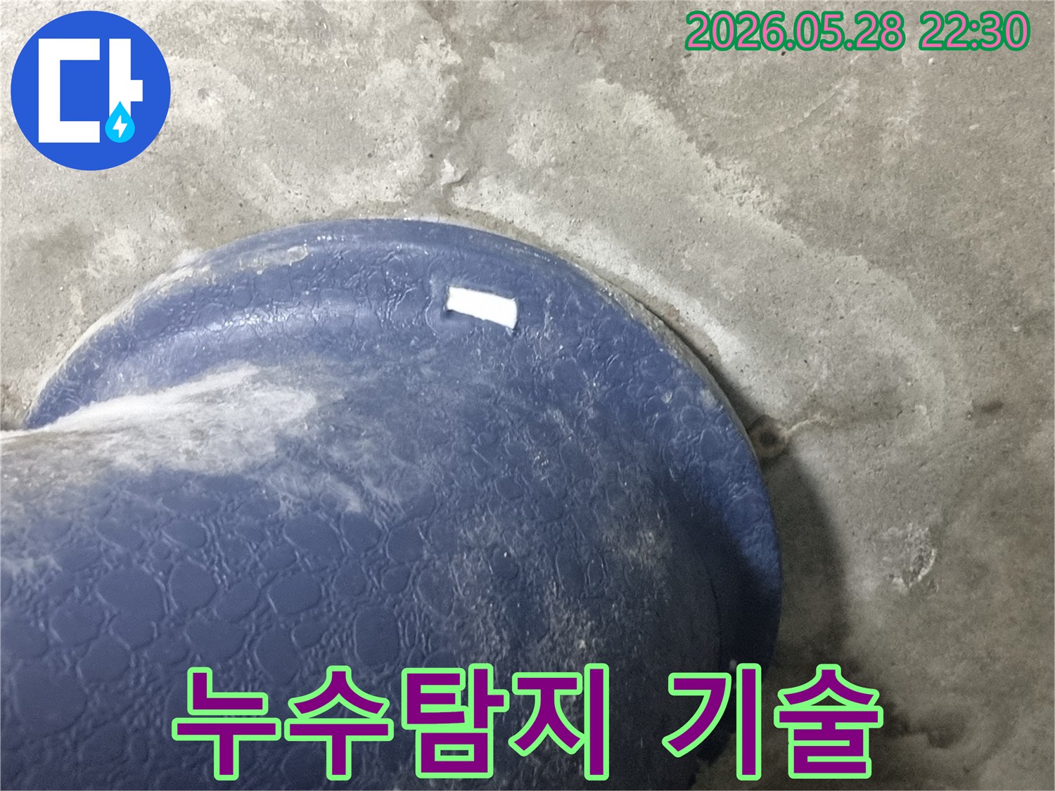 콘크리트 바닥의-파란색 배관-주변에-물이-새어-나와-젖은-모습을-보여주는-누수-탐지-업체의-현장-사진
