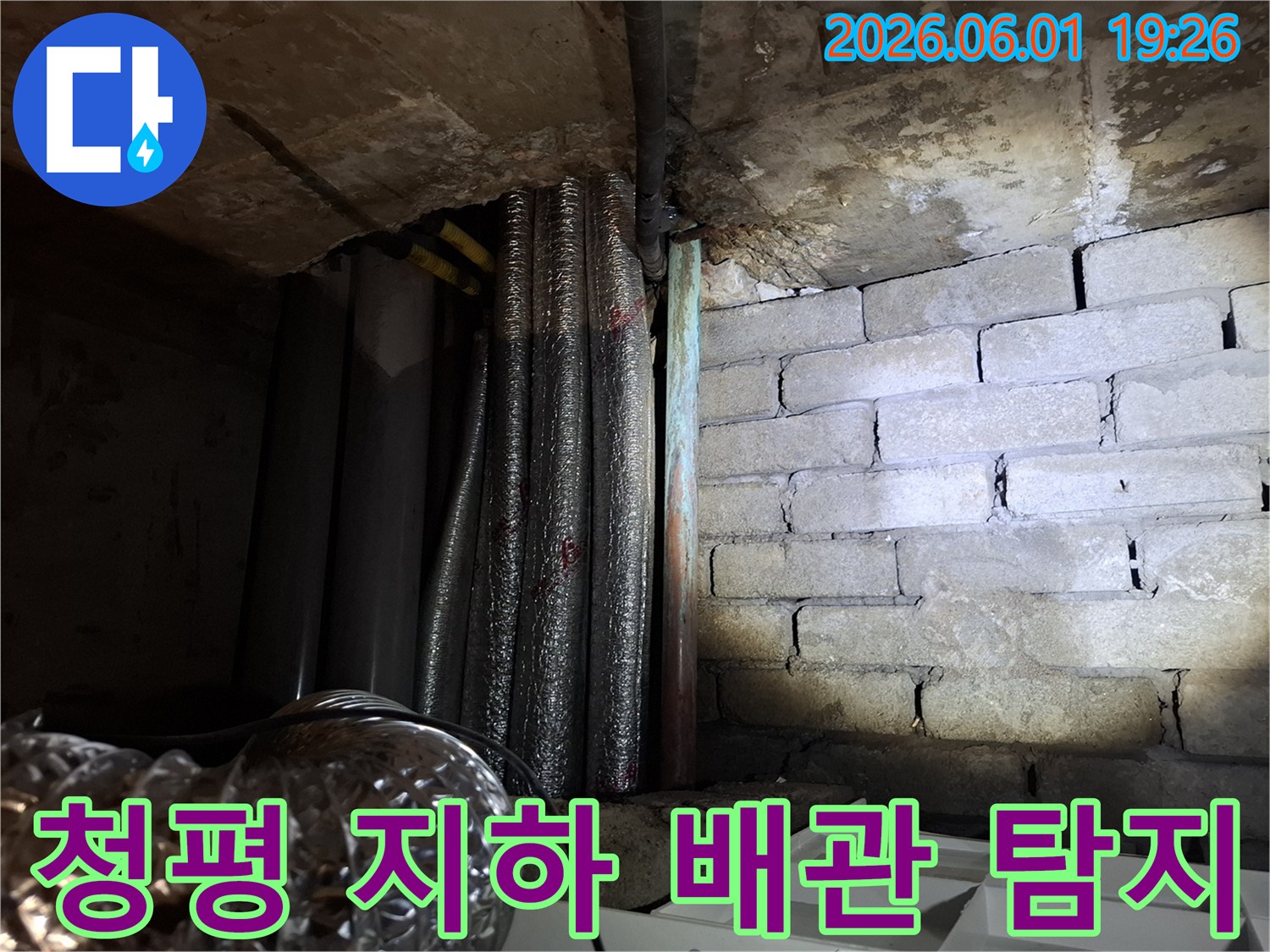 어두운 지하 공간에서-천장 배관과-벽돌 벽면의-누수 흔적을-확인하는 모습의-누수탐지 현장 사진입니다