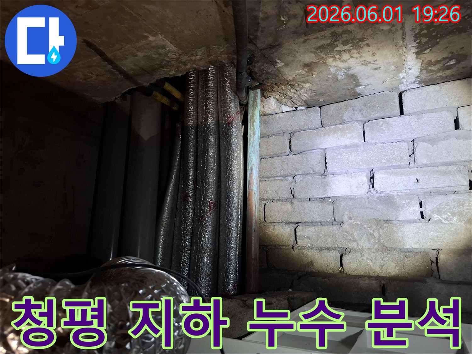 어두운 지하 공간에서-천장 배관과-벽돌 벽면의-누수 흔적을-확인하는 모습의-누수탐지 현장 사진입니다