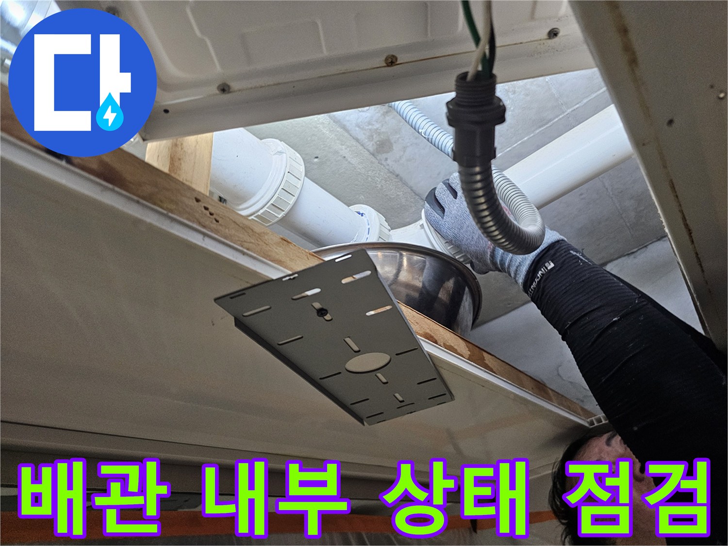 점검구 안쪽의 흰색 PVC 배관과 유연한 호스 연결 부위