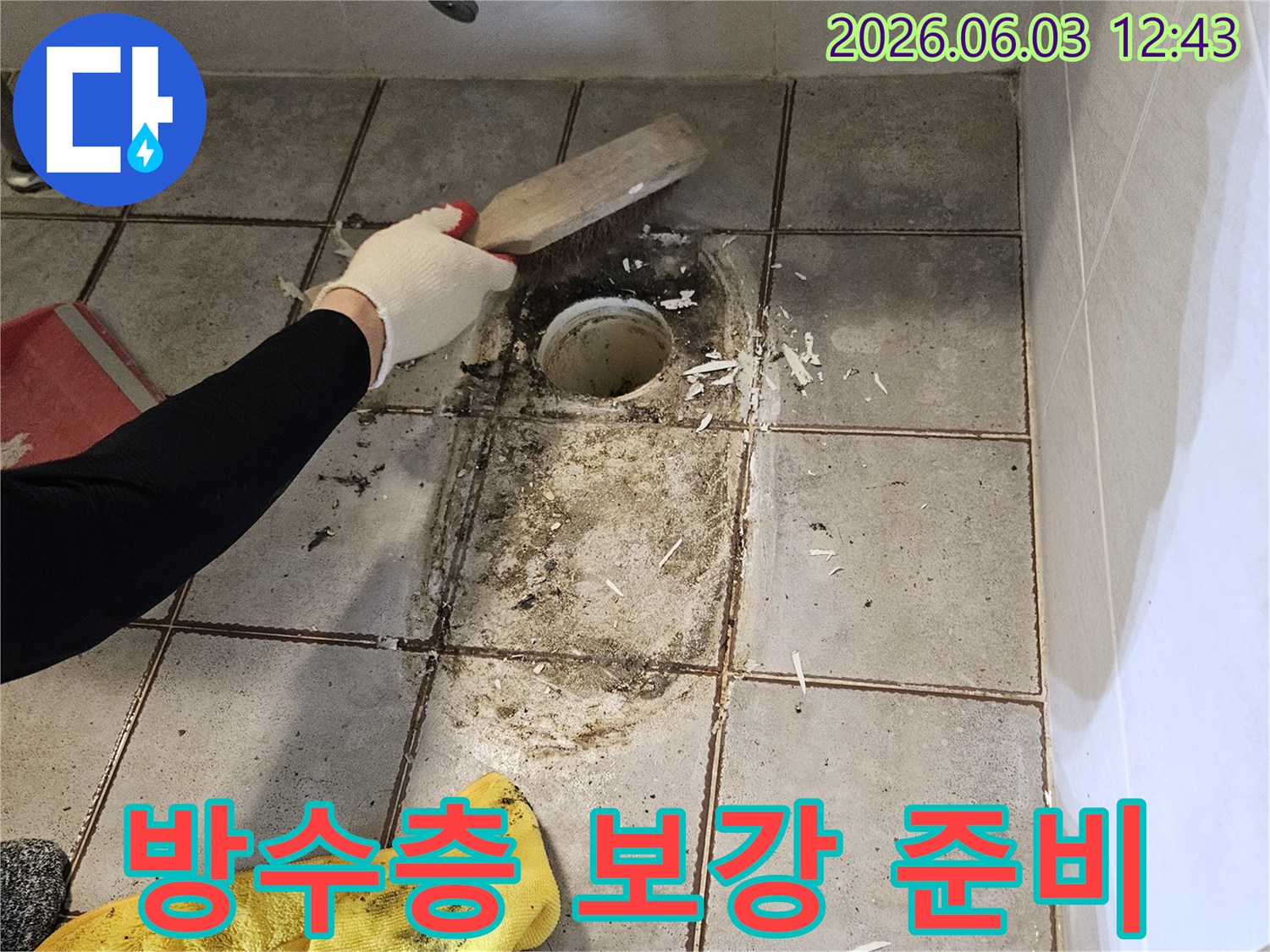누수 공사 중-엔지니어가-욕실 바닥-배수구 주변의-오염된 이물질을-스크래퍼로-제거하는 모습